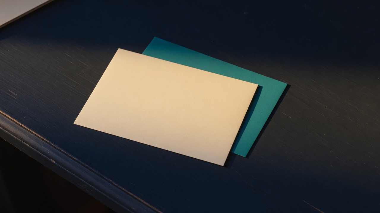 Cream stationery and a teal accent on a dark navy desk