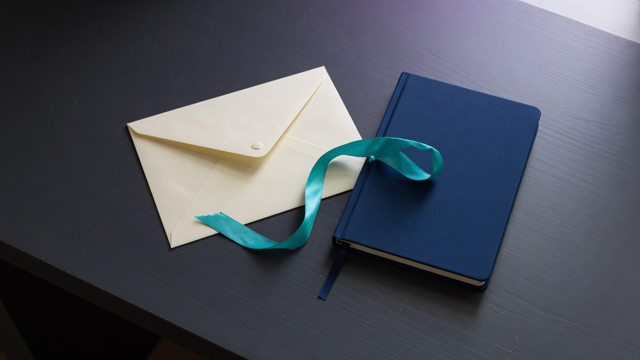 Cream stationery and a teal accent on a dark navy desk